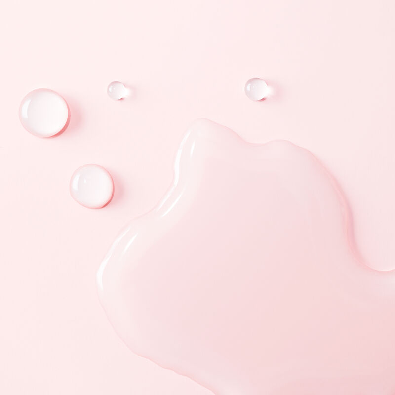Extreme close up of Clinical Solutions Ferulic + Niacinamide Brightener droplets from the Best-in-Brightness Bundle against a light pink background