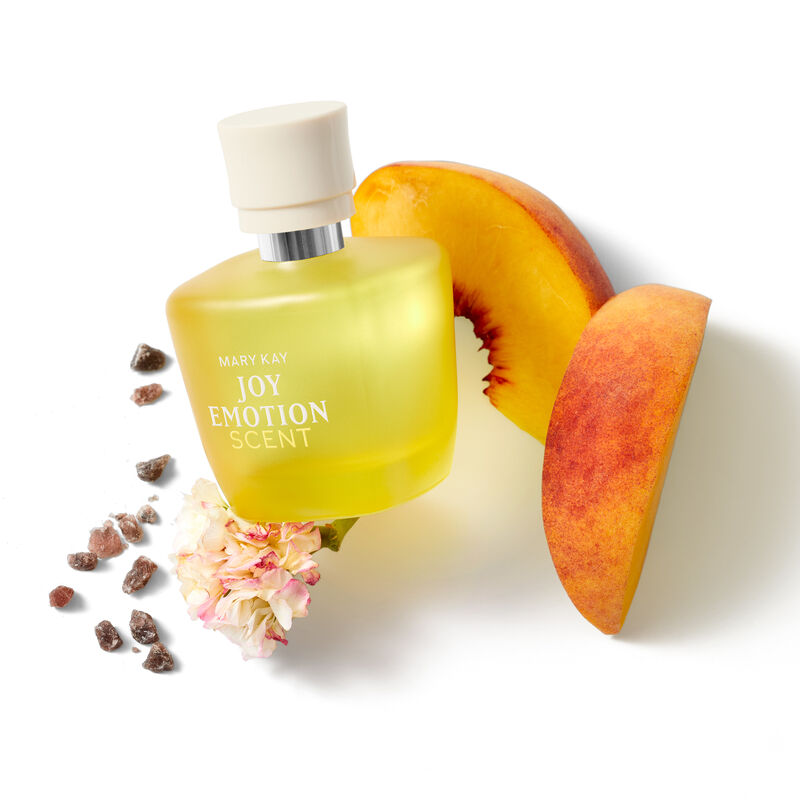 Mary Kay Joy Emotion Scent Eau de parfum yellow bottle surrounded by peaches, geranium and musk on white background. 