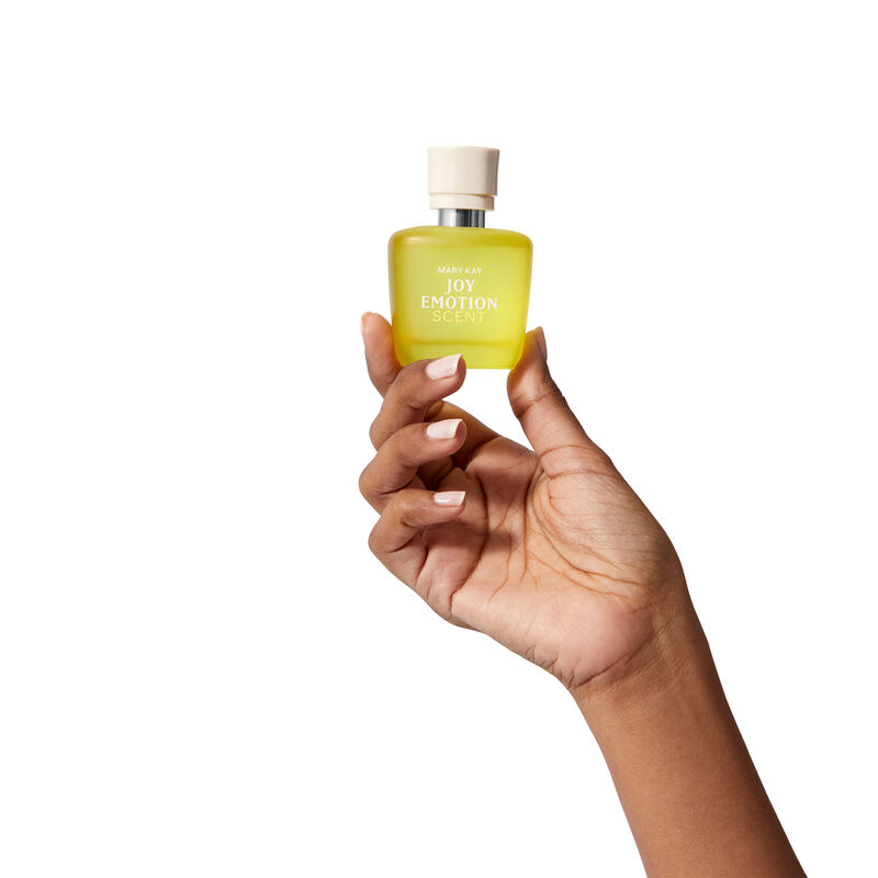 Mary Kay Joy Emotion Scent Eau de parfum yellow bottle held in hand on white backdrop.