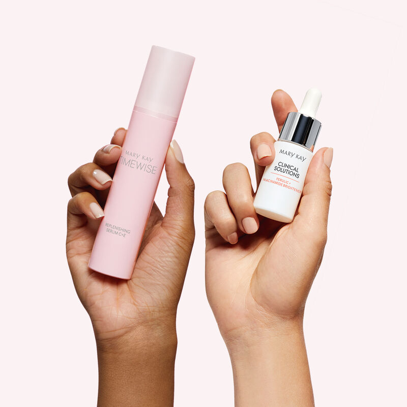Two hands of contrasting skin tones each holding a bottle from the Best-in-Brightness Bundle against light pink background