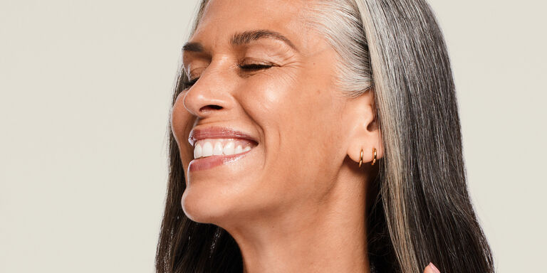 Mujer madura sonriendo con los ojos cerrados.