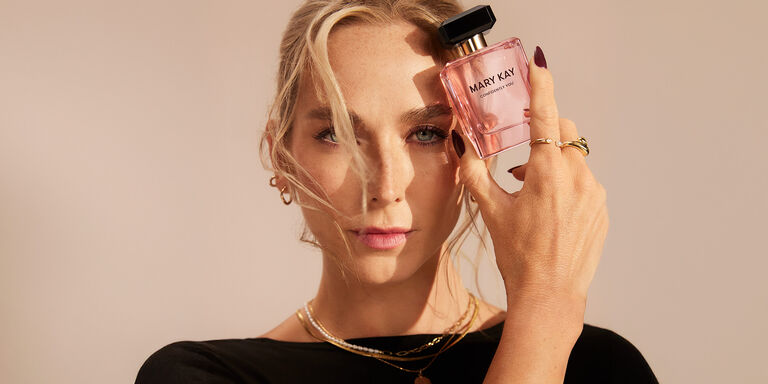 Mujer sosteniendo un frasco de Mary Kay Confidently You Eau de Parfum junto a su rostro.