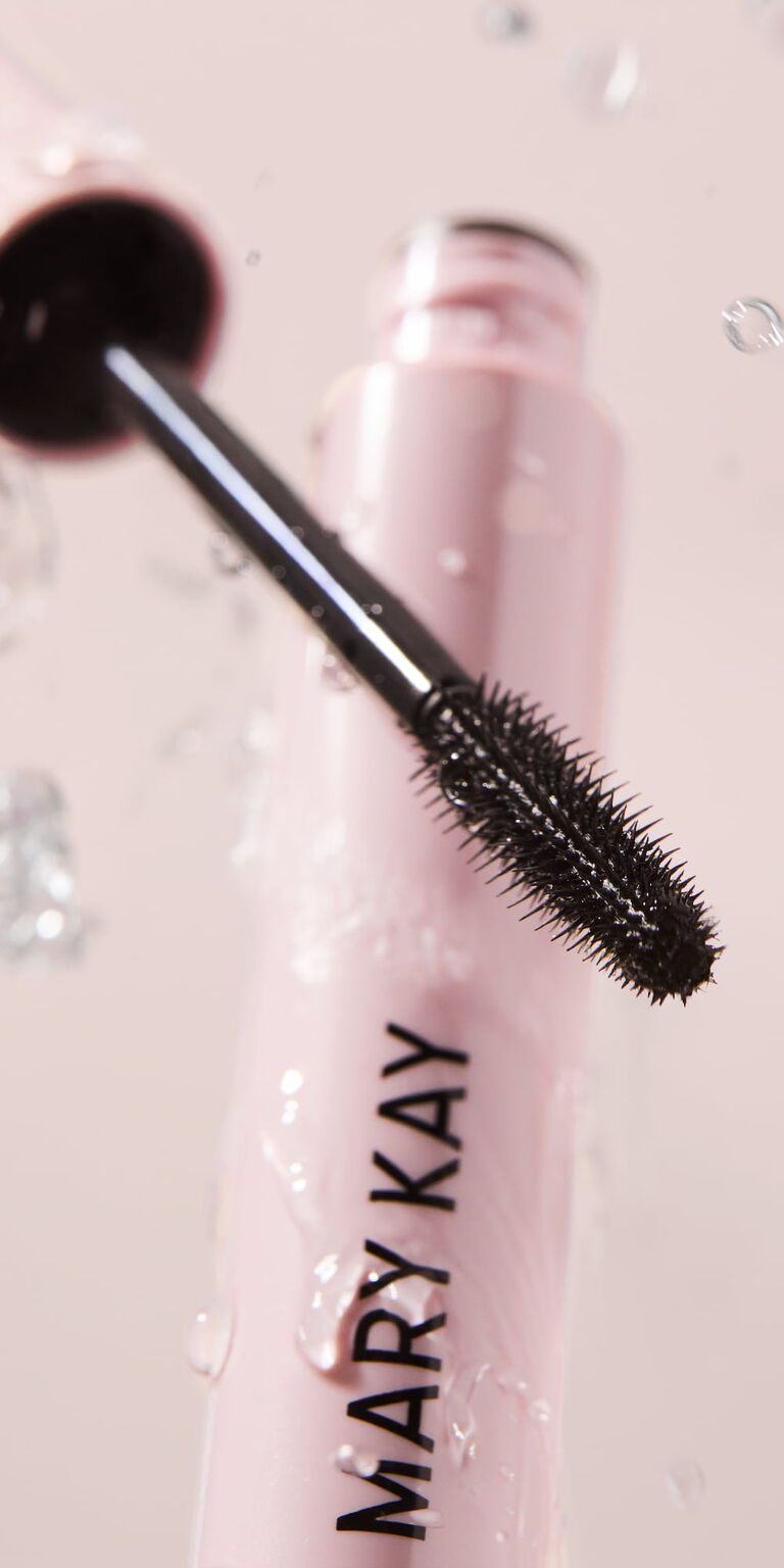 Cepillo y tubo de M&aacute;scara de Pesta&ntilde;as Mary Kay Great Heights Waterproof con gotas de agua sobre ellos.