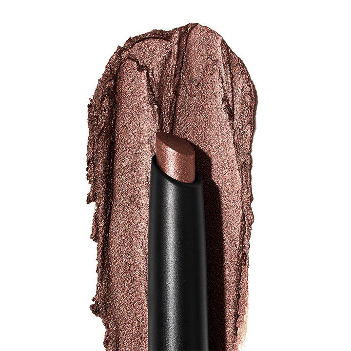 Sombra de Ojos Brillante en Barra Mary Kay&reg; con una muestra de textura al fondo.