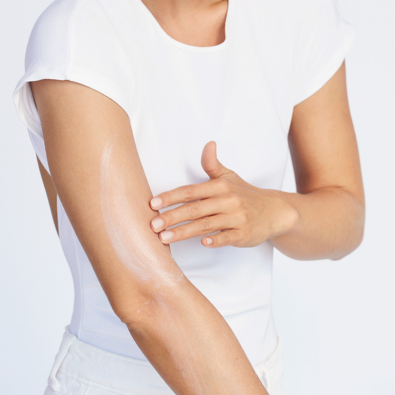 Modelo con tono de piel medio aplicando Protector Solar FPS 50 Mary Kay en la parte superior del brazo