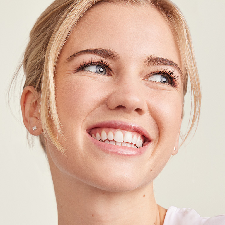 Mujer de piel clara sonriendo hacia un lado de la c&aacute;mara.