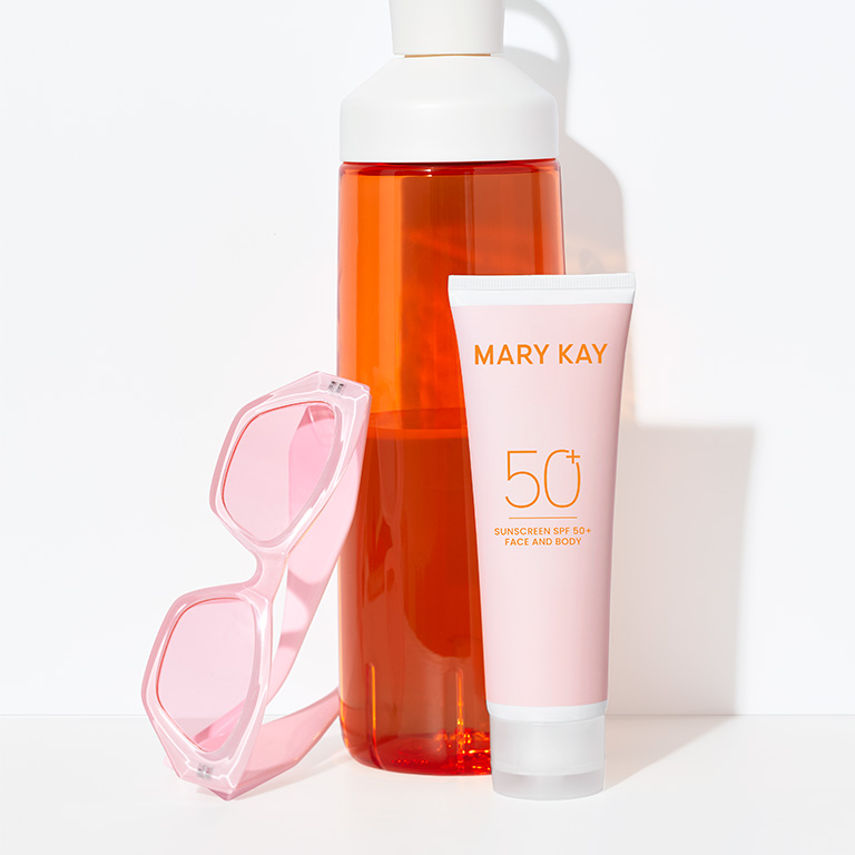 Protector Solar FPS 50 Mary Kay junto a una botella de agua naranja y unas gafas de sol rosas, como imprescindibles del verano.