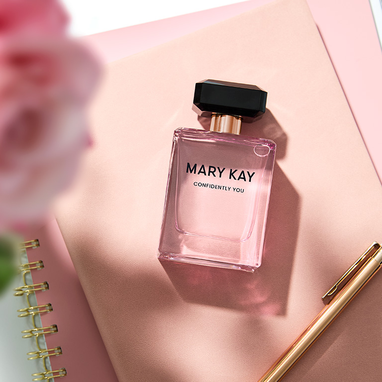 Frasco de Confidently You Eau de Parfum sobre un bloc de notas rosa.