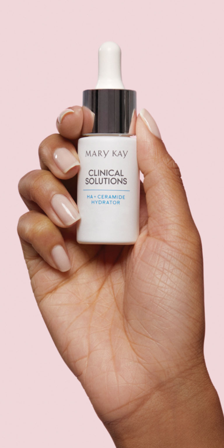 Modelo sosteniendo el frasco de Potenciador AH + Ceramida Hidratante Mary Kay Clinical Solutions sobre un fondo rosa.