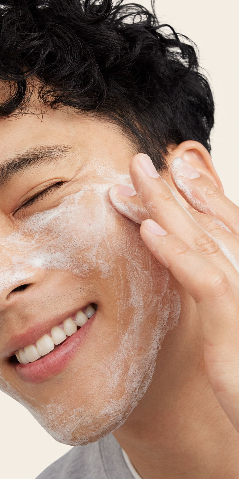 Modelo masculino aplicando Limpiadora Facial MKMen&reg; en el lateral de su rostro.