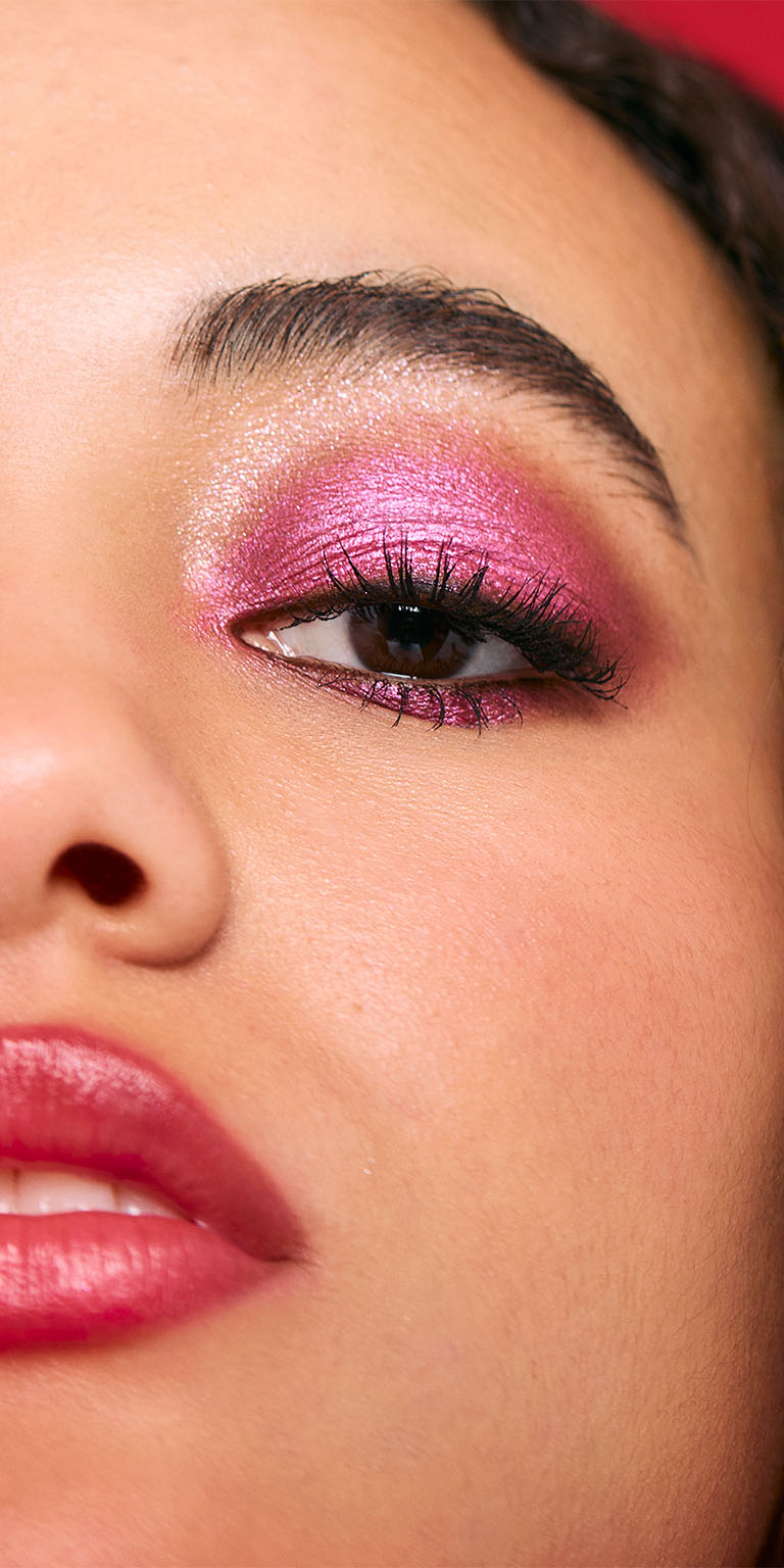 Mujer con tono de piel medio luciendo un look de sombras moradas con brillo.