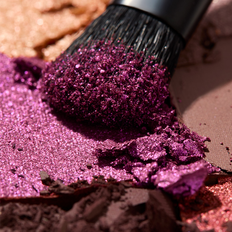 Brocha de sombras de ojos y textura de una sombra morado intenso.